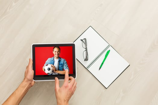 Hand holding tablet with soccer ball flying off screen photo