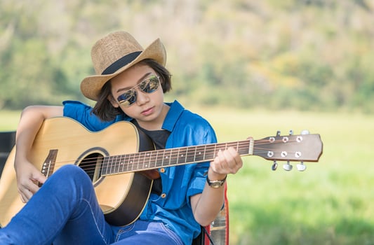 Woman wear hat and playing guitar on pickup truck photo
