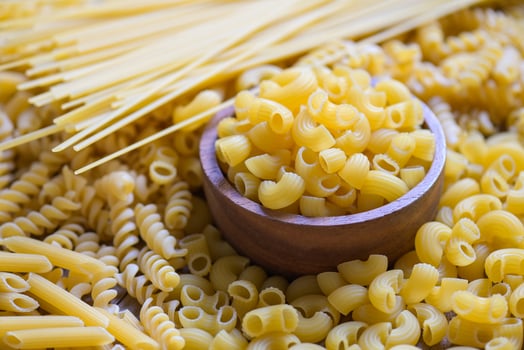 Raw macaroni on wooden bowl, pasta various kinds of uncooked pasta spaghetti and noodles on background, Italian food culinary concept, Collection of different raw pasta for cooking food photo