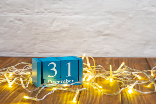 Wooden calendar with 31 december word on glowing garland background, New Year holiday photo