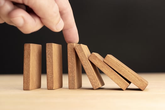 Hand Stopping Falling wooden Dominoes effect photo
