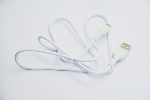 White USB cable for charging the phone on a white background. White cord for charging gadgets. photo