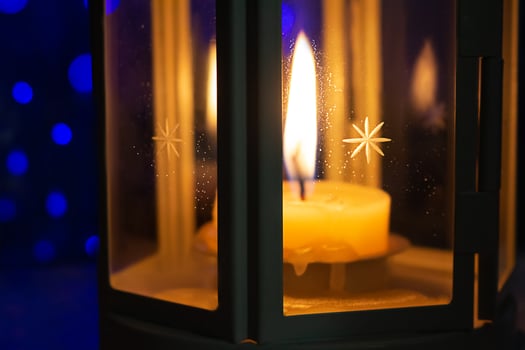 Lantern with burning candle in dark. Behind blue bokeh. Holiday atmosphere, Christmas, New Year. Selective focus photo