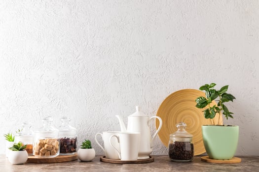 the kitchen background of a modern countertop. coffee pot with mugs, glass eco-jars with cane sugar, coffee beans, a pot with a coffee plant. photo