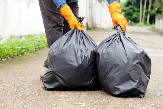 Closeup man holds black plastic bag that contains garbage inside. Concept , Waste management. Environment problems. Daily chores. Throw away rubbish . photo