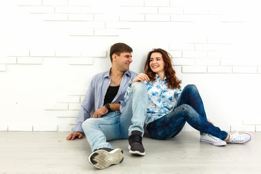 The happy man and woman sit on the background of the white wall photo