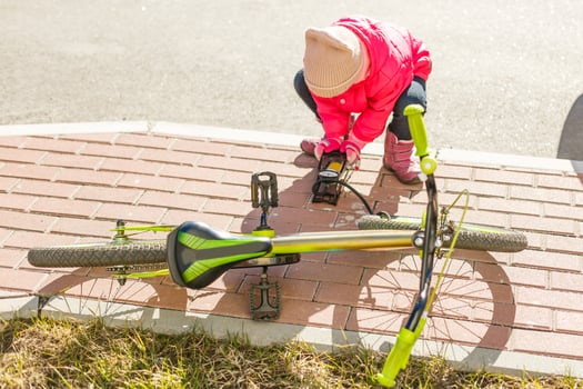 a little girl pumps up a bicycle tire photo