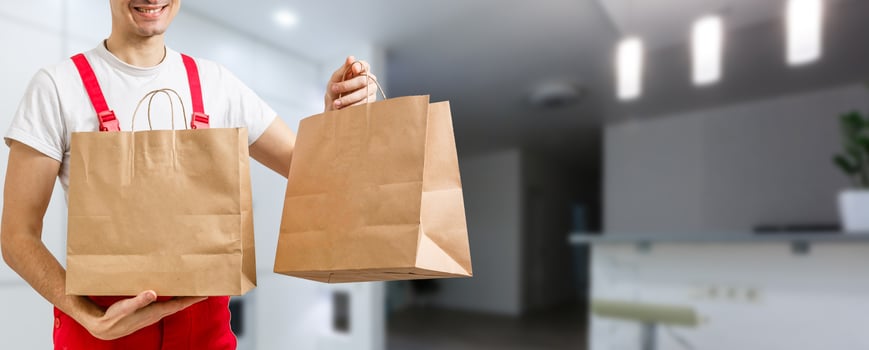 delivery, mail and people concept - happy man delivering food in disposable paper bag to customer home photo