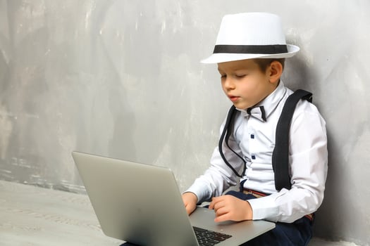 Portrait of Genius. Young boy working on the computer sitting On the floor. Studying. Online learning remotely. Distant school. Distance education. Online courses and knowledge. photo