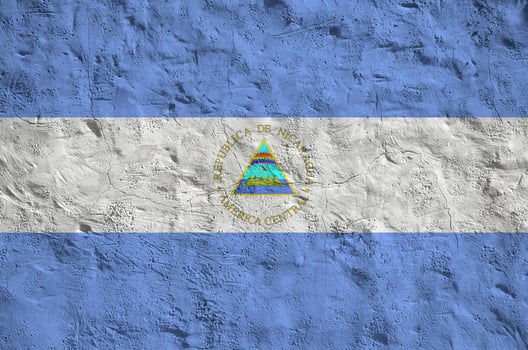 Nicaragua flag depicted in bright paint colors on old relief plastering wall. Textured banner on rough background photo