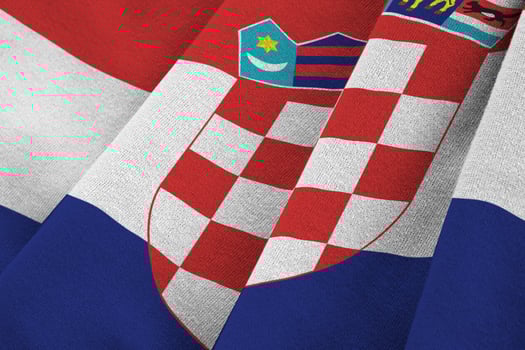 Croatia flag with big folds waving close up under the studio light indoors. The official symbols and colors in banner photo