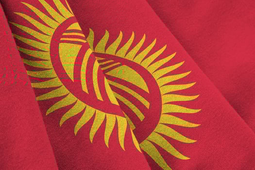 Kyrgyzstan flag with big folds waving close up under the studio light indoors. The official symbols and colors in banner photo