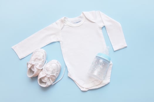 bodysuit for a newborn, bottle and booties on a blue background photo