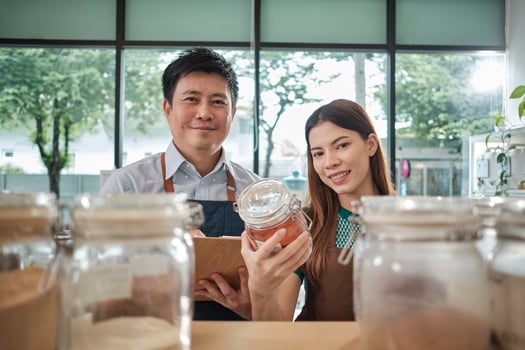 Portrait of two shopkeepers with natural organic products in reusable glass jars, smile and look at camera in refill store, zero waste, plastic-free grocery, and eco-friendly, sustainable business. photo