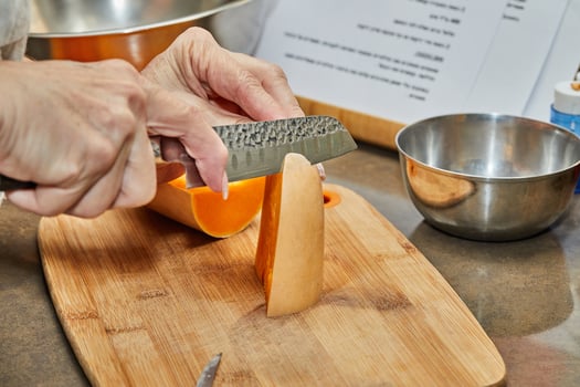 Chef cuts pumpkin in the shape of pear on wooden board in the home kitchen photo