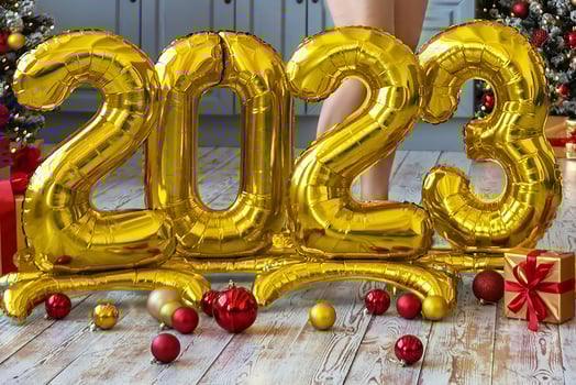 A golden balls in the form of numbers 2023 on the background of a Christmas tree. People are celebrating the new year, waiting, anticipating. The concept of the new year and celebration. photo
