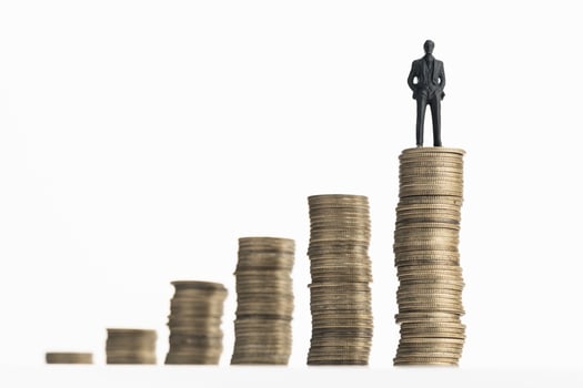 Businessman standing on stack of growing coins photo