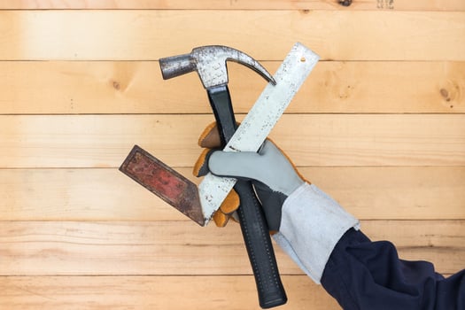 Hand in glove holding iron ruler and hammer photo