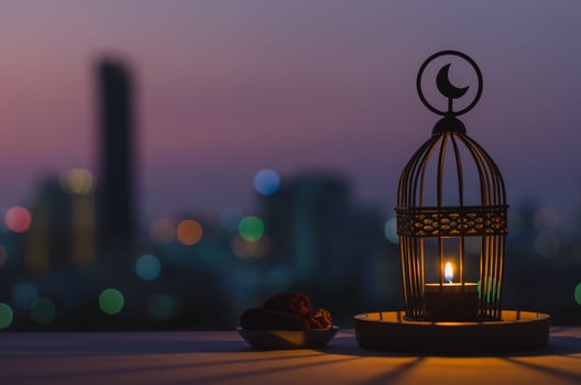 Lantern that have moon symbol on top and small plate of dates fruit with dusk sky and city bokeh light background for the Muslim feast of the holy month of Ramadan Kareem. photo