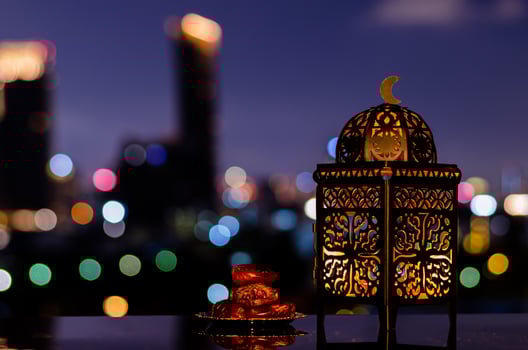 Lantern and small plate of dates fruit with night sky and city bokeh light background for the Muslim feast of the holy month of Ramadan Kareem. photo