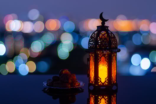 Selective focus of lantern that have moon symbol on top and small plate of dates fruit with city bokeh light background for the Muslim feast of the holy month of Ramadan Kareem. photo