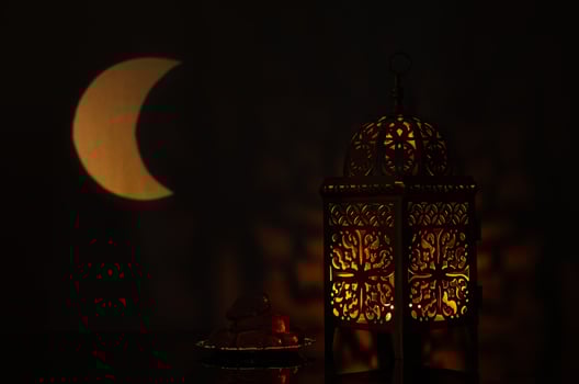 Lantern and small plate of dates fruit with moon shape from light on background for the Muslim feast of the holy month of Ramadan Kareem. photo