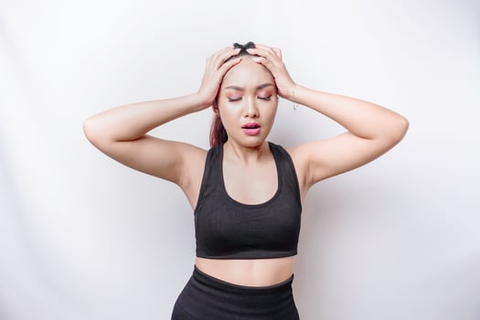 A portrait of an sporty Asian woman wearing a sportswear isolated by white background looks depressed photo