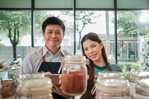 Portrait of two shopkeepers with natural organic products in reusable glass jars, smile and look at camera in refill store, zero waste, plastic-free grocery, and eco-friendly, sustainable business. photo