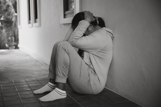 Schizophrenia with lonely and sad in mental health depression concept. Depressed woman sitting against floor at home with dark room feeling miserable. Women are depressed, fearful and unhappy. photo