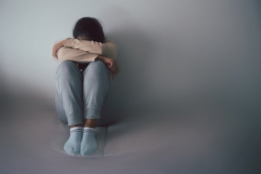 Schizophrenia with lonely and sad in mental health depression concept. Depressed woman sitting against floor at home with dark room feeling miserable. Women are depressed, fearful and unhappy. photo
