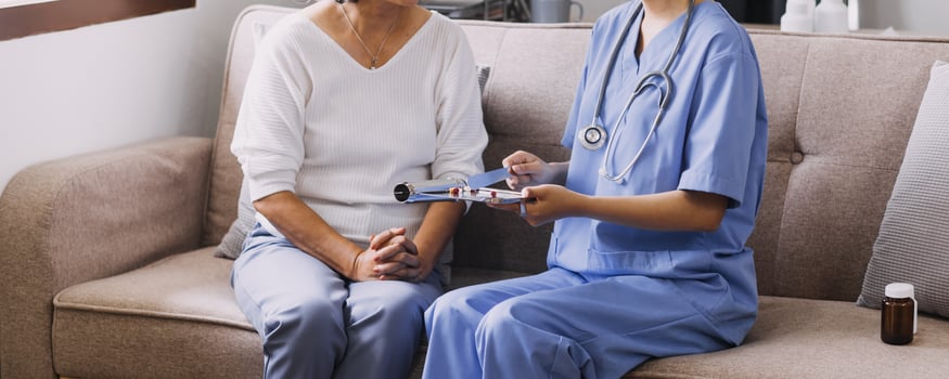 Homecare nursing service and elderly people cardiology healthcare. Close up of young hispanic female doctor nurse check mature caucasian man patient heartbeat using stethoscope during visit photo