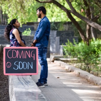 Indian couple posing for maternity baby shoot. The couple is posing in a lawn with green grass and the woman is falunting her baby bump in Lodhi Garden in New Delhi, India photo