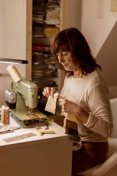 Caucasian brunette woman sewing fabric with a vintage, retro sewing machine. Fashion, creation and tailoring. Process of sewing in atelier or workshop. Special hobby. Cozy interior and warm colors. photo