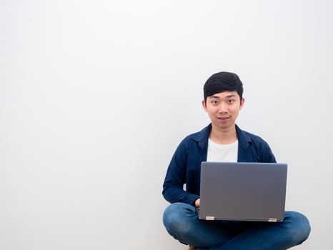 Asian man happy face using laptop sitiing on the chair on white wall background photo