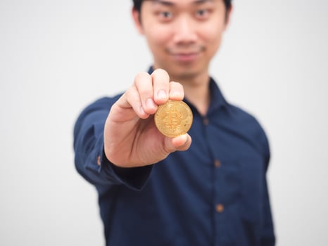 Closeup golden bitcoin in man hand cheerful white background photo