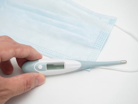 Closeup hand holding thermometer and face mask protect virus white background photo