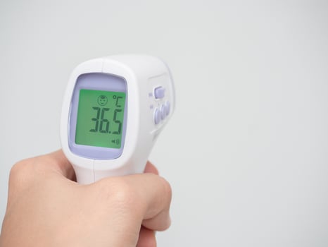 Hand holding infrared thermometer digital at white background photo