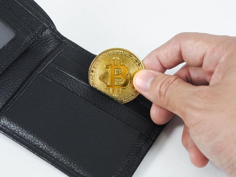 Closeup hand pick up golden bitcoin at wallet white background photo