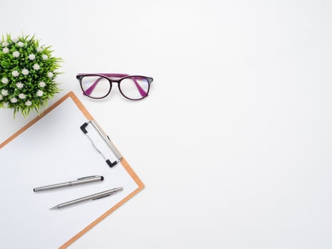 Document board with pen and glasses with vase on the table top view copy space photo