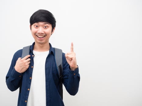 Asian man with school backpack smile face point finger up get idea portrait copy space white background photo