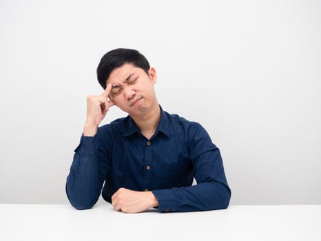Young man sitting at the table feeling strain and touch his head photo