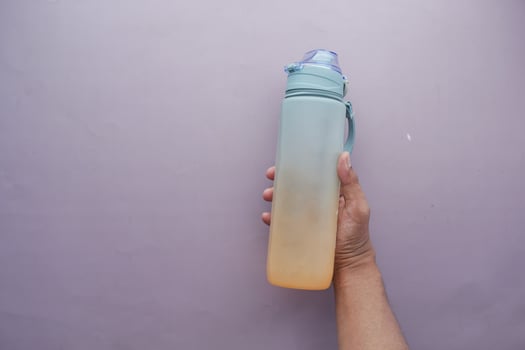 hand holding sport bottle on purple background photo