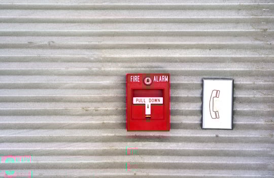 The red fire alarm is attached to the wall and the cement wall of the factory to be used as a warning system when there is a fire. photo
