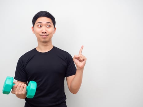 Asian man holding drumbbell happy face point finger at copy space motivation for workout concept photo