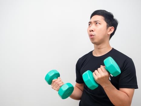 Asian man holding drumbbell feeling amazed and looking at copy space white background photo