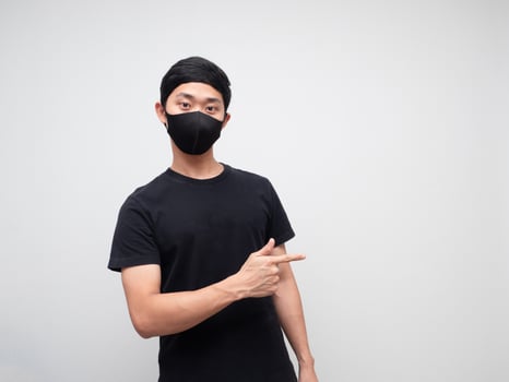 Portrait man wearing mask point finger right side and looking at camera on white background photo