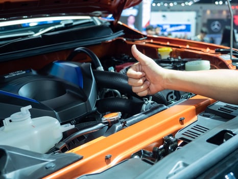 Hand thumb up with the engine of new car photo