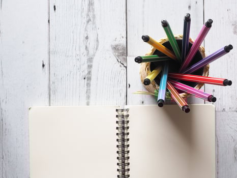 Pen colorful array circular in box with open notebook blank page on white wood table and nature light of sun idea concept top view,business and education photo
