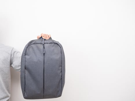 Man hand holding backpack white isolated photo