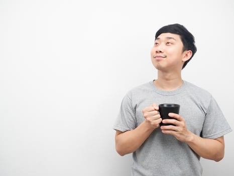 Man holding coffee cup gesture dreaming and looking at copy space photo